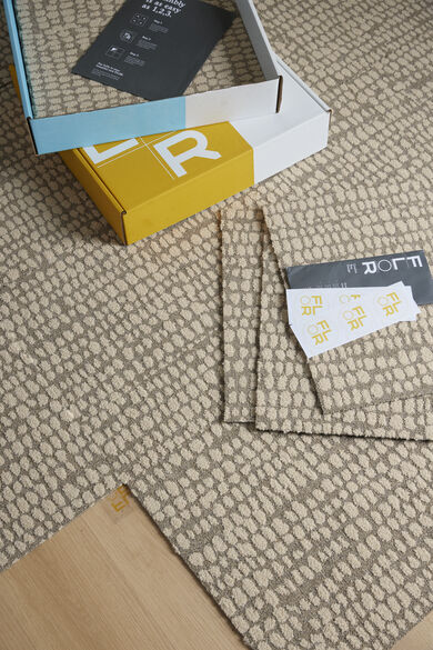 Open box of FLOR carpet tiles with FLORdots on top of a closed box of FLOR carpet tiles. 